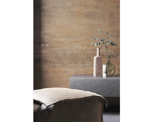 Rumsbild med en puff, ett sidobord och dekorativa föremål framför en mönstrad vägg