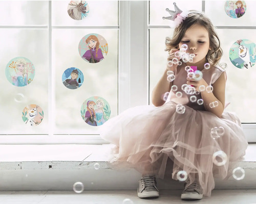 Flicka med krona blåser såpbubblor framför ett fönster med klistermärken från Frost