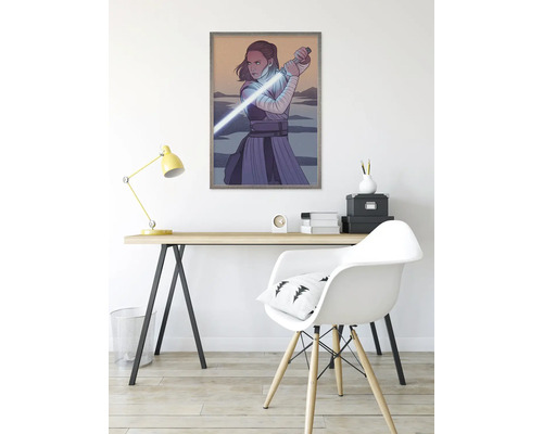 Inramad Star Wars-affisch med Rey och ljussabel på ett skrivbord