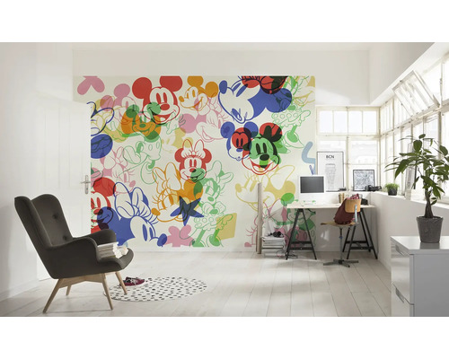 Ljust rum med en väggtapet med Musse Pigg-motiv, ett skrivbord och en fåtölj.