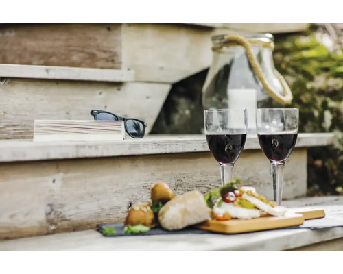 Miljöbild med två glas rött vin, tilltugg och solglasögon på en trätrappa
