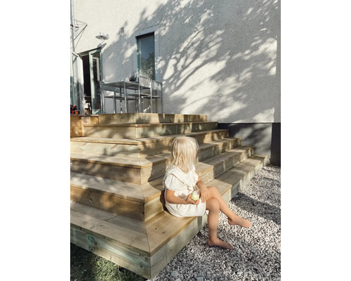 Flicka sitter på trätrappa i trädgården