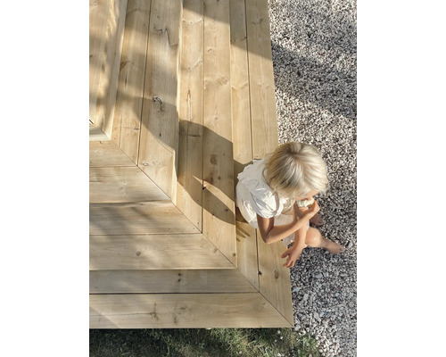 En kvinna sitter på en trätrappa i trädgården.