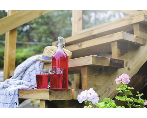 Flaska och två glas med dryck på en trätrappa utomhus