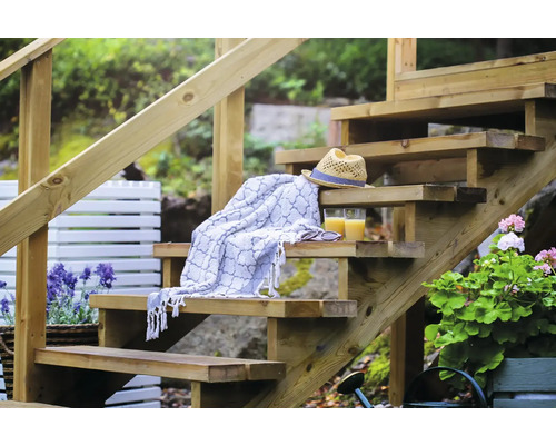 Trätrappa med handduk, hatt och drycker i trädgården