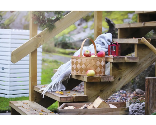 Trätrappa med korg med äpplen, filt och lykta i trädgården