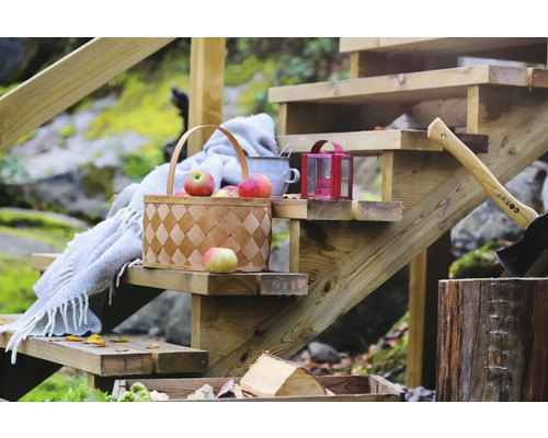 Trätrappa dekorerad med korg full av äpplen, filt, lykta och yxa