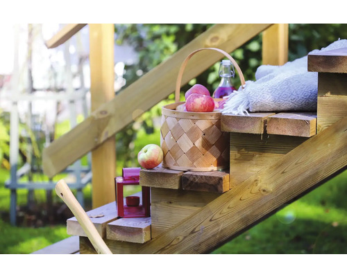 Dekorativ korg med äpplen på en trätrappa i trädgården