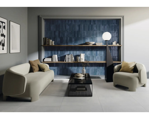 Vardagsrum med soffa, fåtölj, soffbord, bokhylla och blå väggplattor