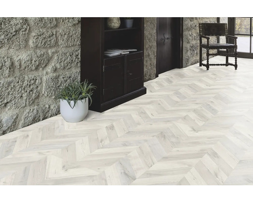 Ljust rum med parkettgolv i fiskbensmönster, stentrappa och mörkt träskåp.