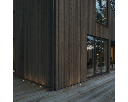 Träfasad med infällda markspotlights för utomhusbelysning.