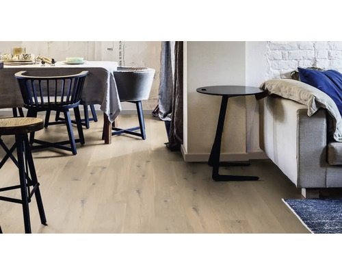 Ljust rum med trägolv, stolar och sidobord bredvid en soffa.