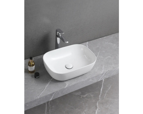 Tvättställ i keramik med armatur på en bänkskiva