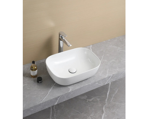 Tvättställ i keramik på en bänkskiva med blandare