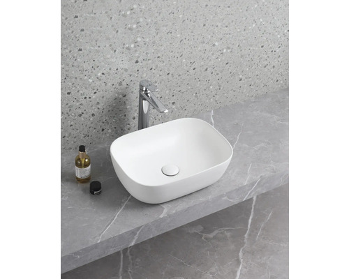 Tvättställ av keramik på en bänkskiva med armatur