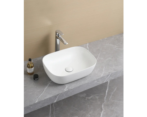 Tvättställ i keramik på en bänkskiva i ett badrum.