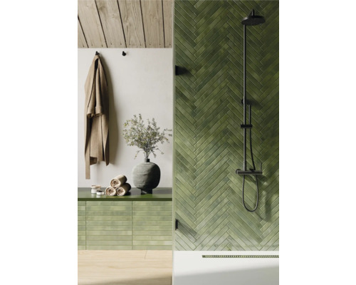 Badrum med grönt kakel i fiskbensmönster, dusch och handdukar