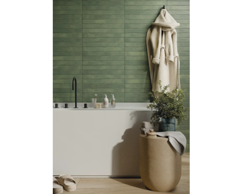 Badrum med grönt kakel, badkar och badrock