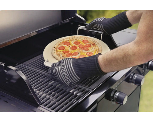 Pizza på pizzasten läggs på en gasolgrill