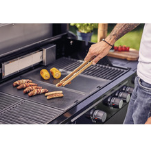 Man grillar korvar och majskolvar på en grill