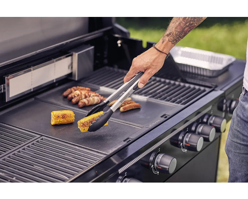 Person grillar majs och korv på en grill.