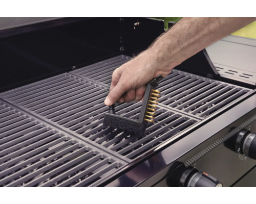 En person rengör ett grillgaller med en grillborste.