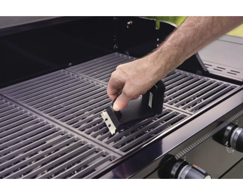 En person rengör ett grillgaller med en grillborste.