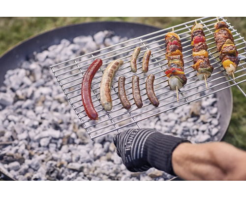 Grillmat på ett grillgaller ovanför träkol, inklusive korvar och shashlikspett.