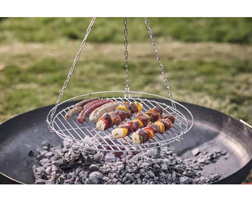 Roterande grill med korvar och köttspett över kol