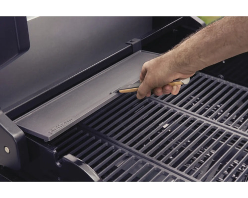 En man lägger en grillplatta på ett grillgaller.