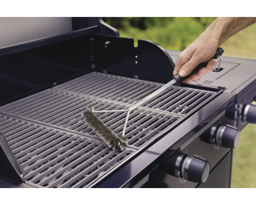 En person rengör ett grillgaller med en grillborste.