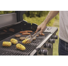 Grill med grillade produkter som majskolvar, korvar och hamburgare, en person använder en grilltång.