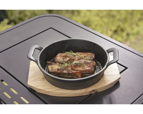 Grillat kött med rosmarin i en svart gjutjärnspanna på ett träbord