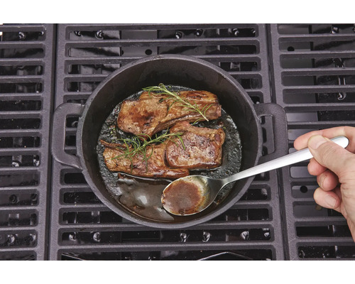 Två biffar med rosmarin tillagade i en gjutjärnspanna på en grill