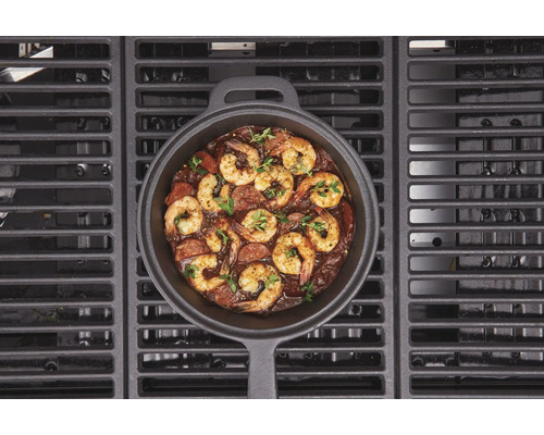 Gjutjärnspanna med räkor och korv på en grill