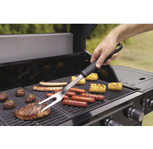 Person använder grillgaffel på en grill med olika livsmedel.