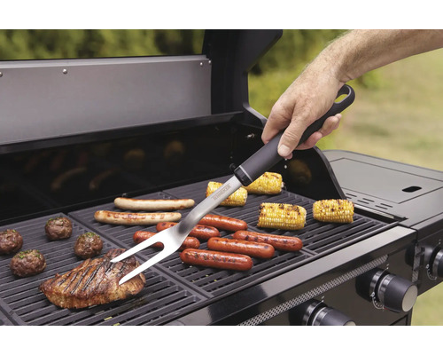 Person använder grillgaffel på en grill med olika livsmedel.