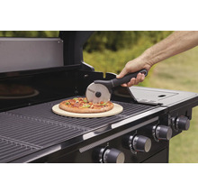 Person skär pizza på grill med pizzasten och pizzaskärare