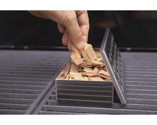 Fyllning av en rökbox med rökflis på en grill