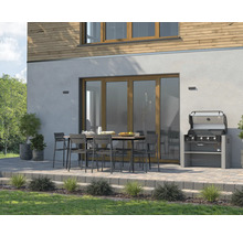 Uteplats med trädgårdsgrill, matbord och stolar framför ett hus