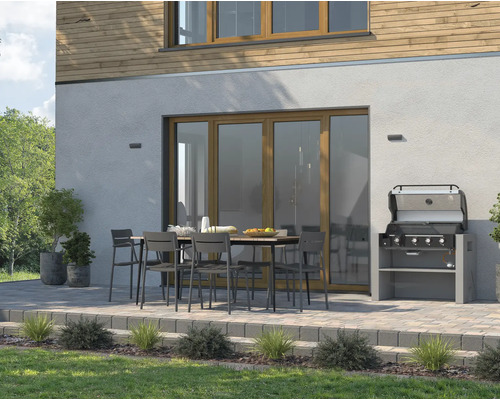 Uteplats med trädgårdsgrill, matbord och stolar framför ett hus