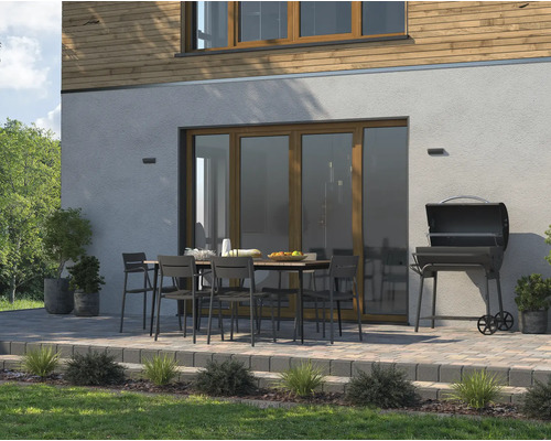 Uteplats med trädgårdsbord, stolar och grill på en stenlagd terrass