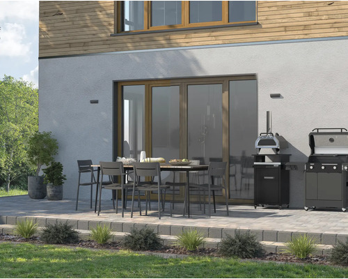 Uteplats med matbord, stolar, pizzaugn och grill