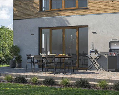 Uteplats med matbord, stolar, grill och pizzaugn framför ett hus