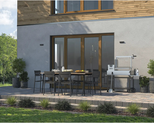 Uteplats med matbord, stolar och grill framför ett hus