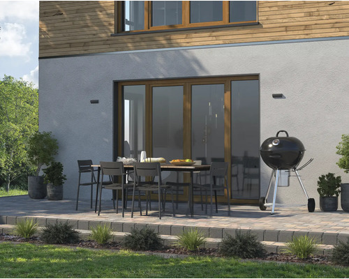 Terrass med grill, trädgårdsbord och stolar framför ett hus