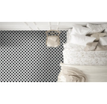 Vy över ett sovrum med golvplattor i ett geometriskt mönster, en stol och en säng