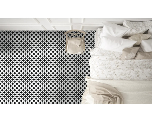 Vy över ett sovrum med golvplattor i ett geometriskt mönster, en stol och en säng