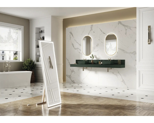 Badrum med badkar, spegel, tvättställ, ovala speglar med belysning och väggplattor i marmorlook