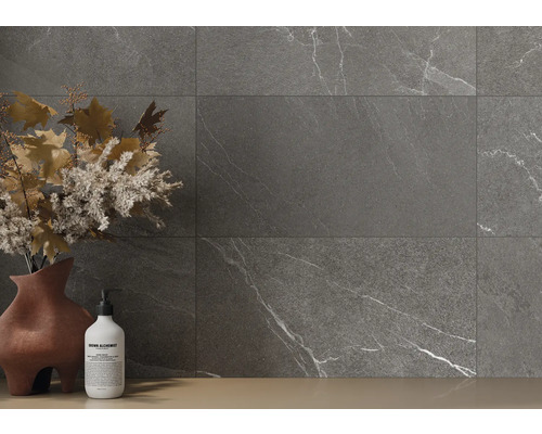 Grå plattor med marmorutseende på en vägg, kompletterat med en vas med blomsterdekorationer och en tvålflaska